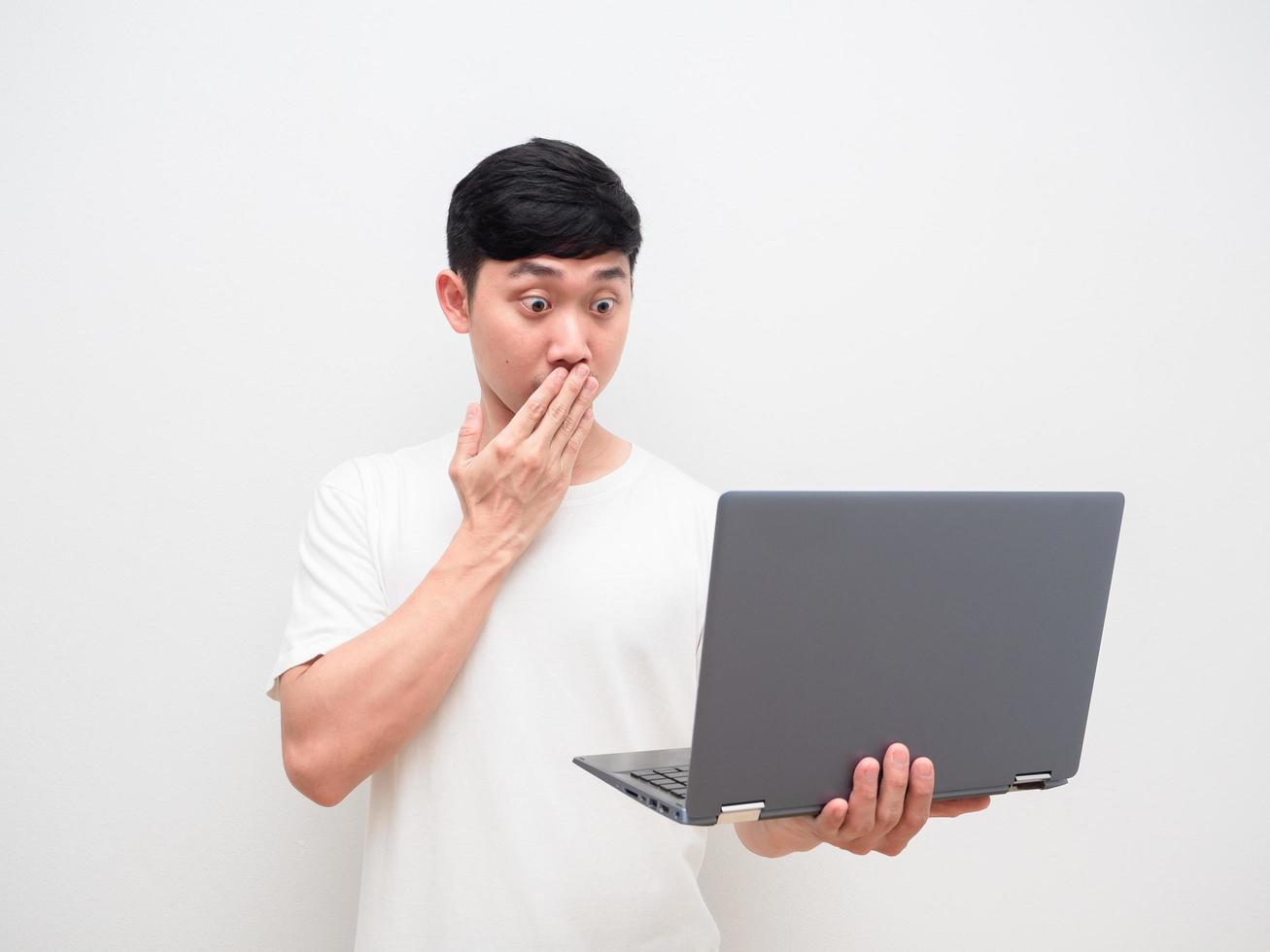 homme asiatique chemise blanche fermer la bouche avec un visage de choc regarder un ordinateur portable à la main sur fond blanc isolé photo