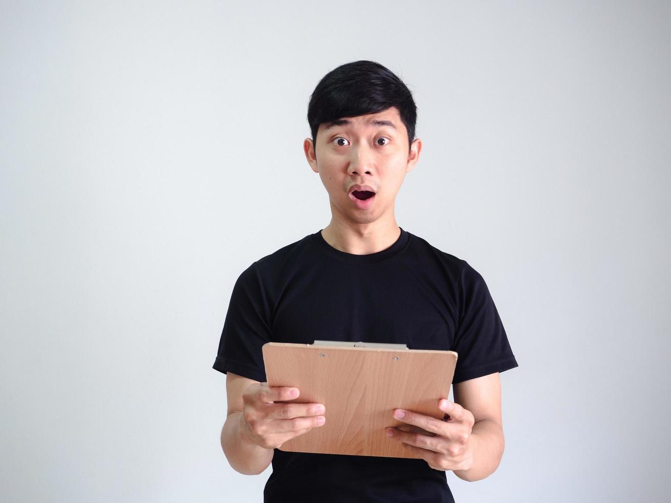 jeune homme chemise noire visage choqué tenant le presse-papiers en bois regarder la caméra sur fond blanc isolé, concept d'entreprise photo