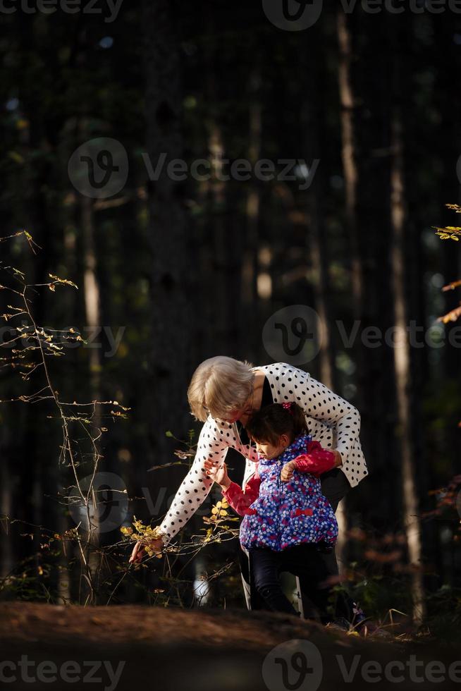 grand-mère et sa petite-fille autiste profitant de vacances ensemble à l'extérieur, allongées sur l'herbe verte sur une couverture et souriant à la caméra. loisirs vie familiale, bonheur et moments. photo