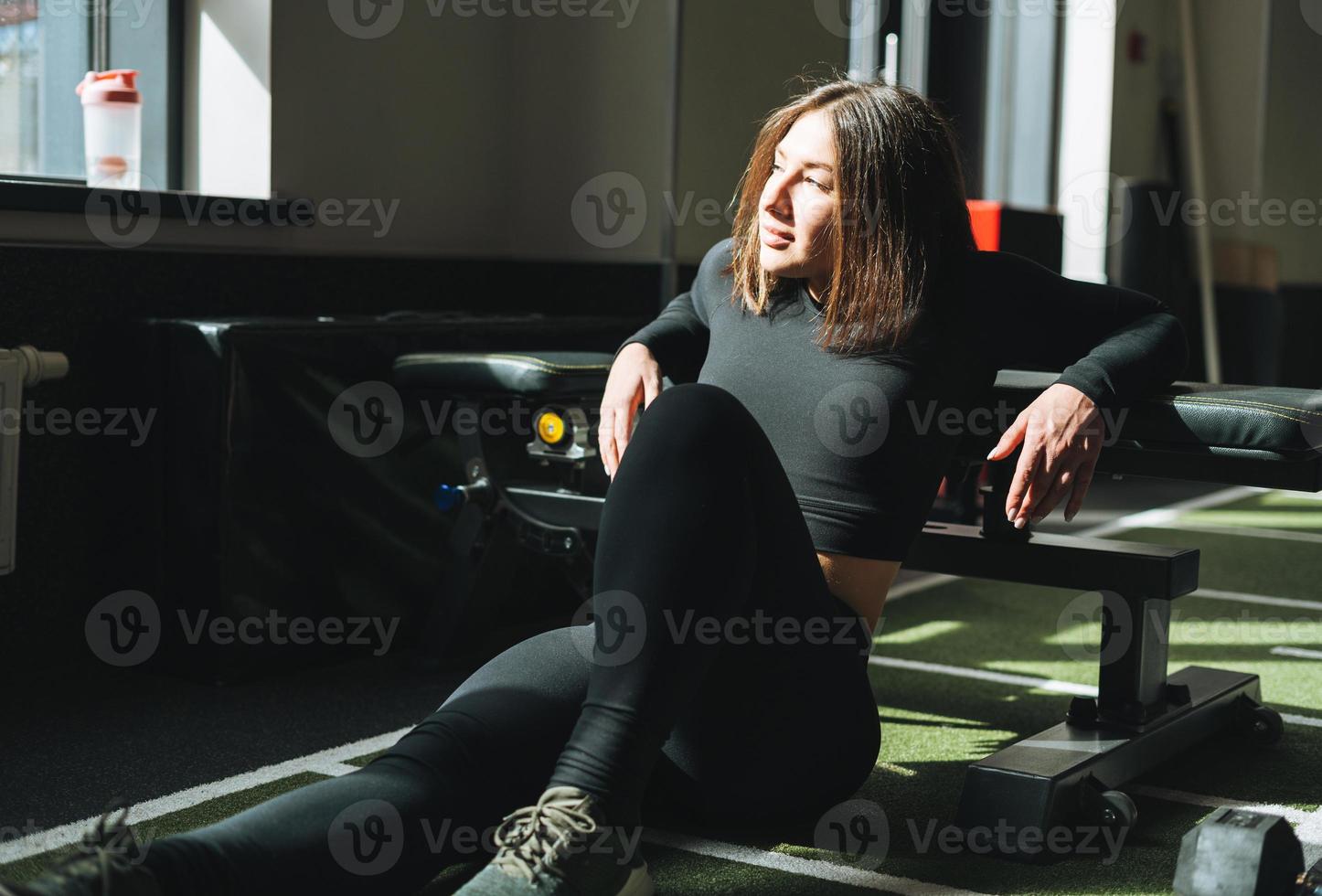 portrait de jeune femme brune au repos en vêtements de sport dans le club de remise en forme photo