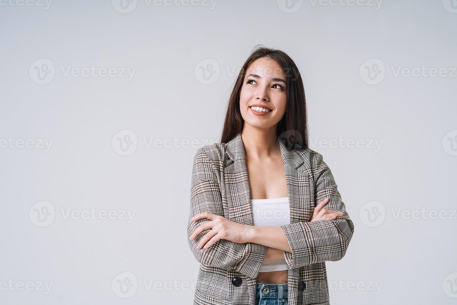 jeune femme asiatique heureuse aux cheveux longs en costume sur fond gris photo
