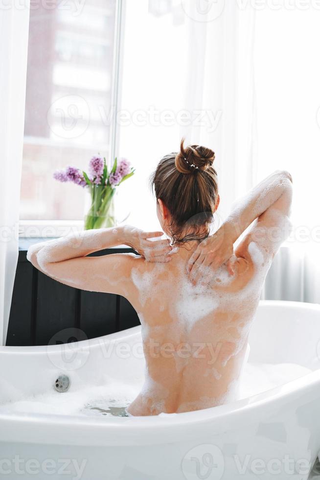 jeune femme heureuse prenant un bain à la maison, faites-vous plaisir photo