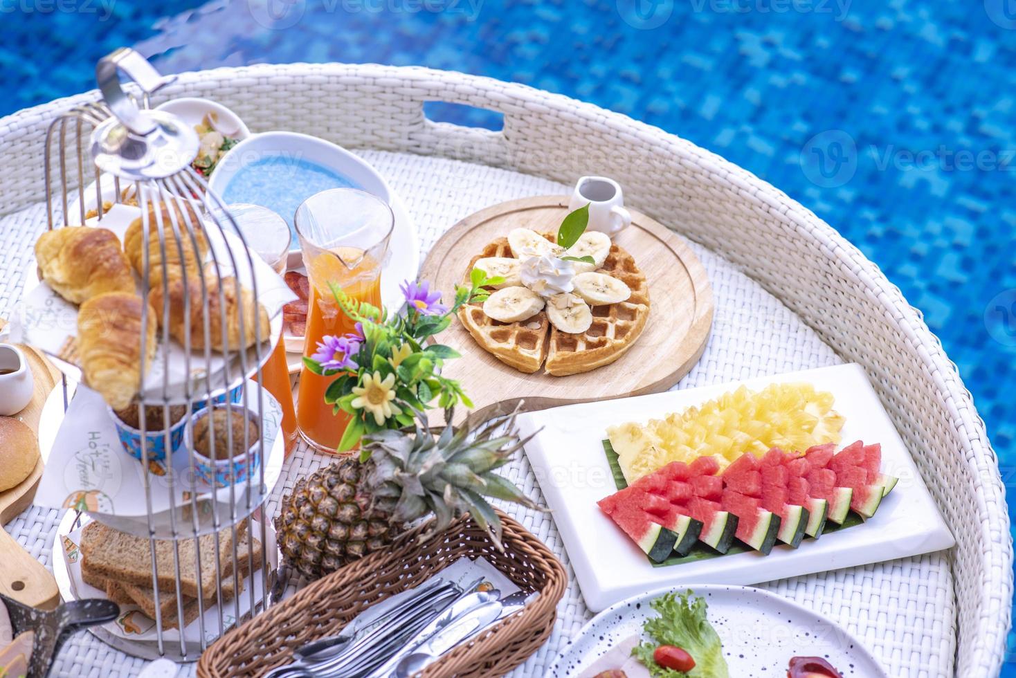 petit-déjeuner dans la piscine, petit-déjeuner flottant dans le complexe de villas. détente dans l'eau calme de la piscine, petit-déjeuner sain et fruits tropicaux. photo