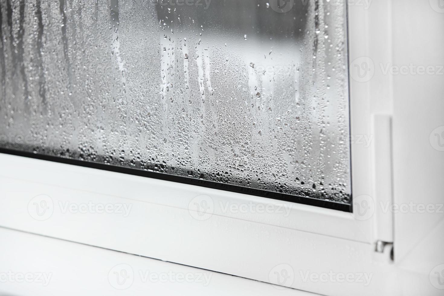 une fenêtre en plastique avec condensation d'eau sur le verre. fenêtre pvc double vitrage. concept fenêtre en plastique défectueuse avec condensation, différence de température, refroidissement, humidité dans la pièce. photo