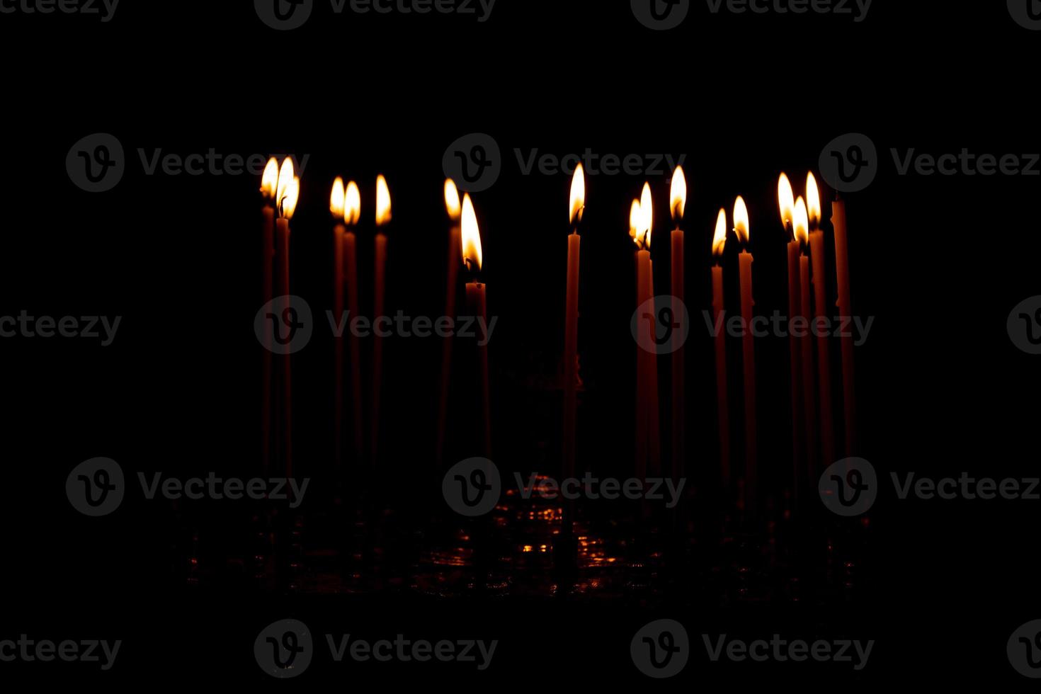 gros plan de beaucoup de bougies allumées isolées sur fond noir. photo