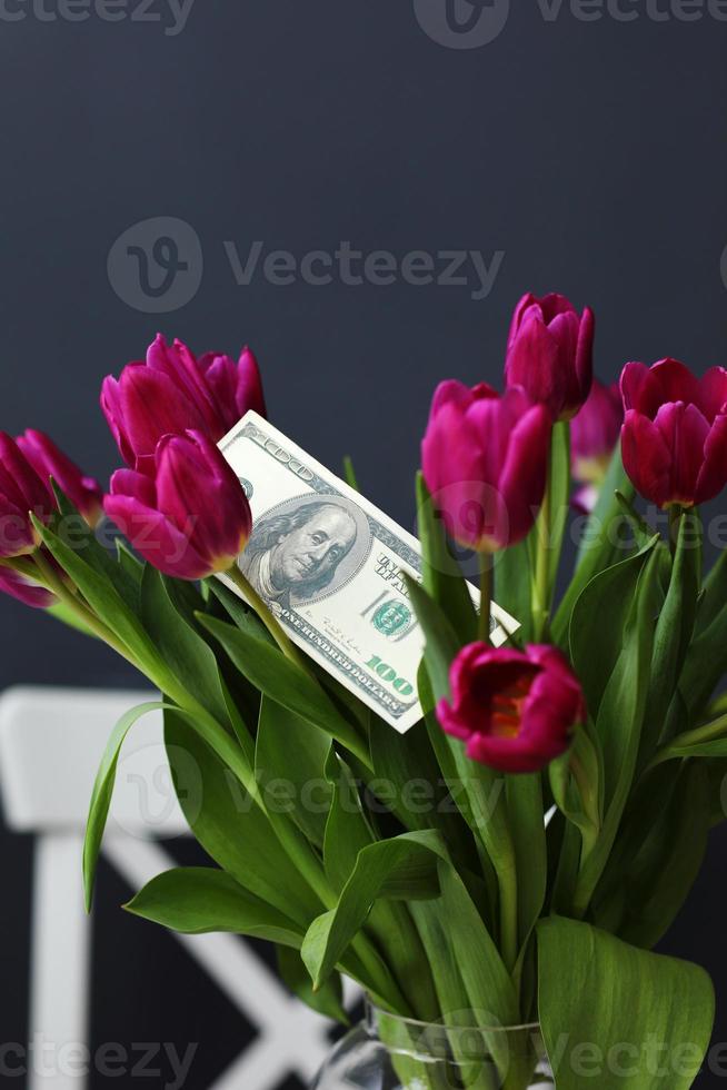 billets de dollars sur bouquet de fleurs de tulipes. mise au point sélective. dépenser en fleurs pour les vacances. commerce de fleurs. photo