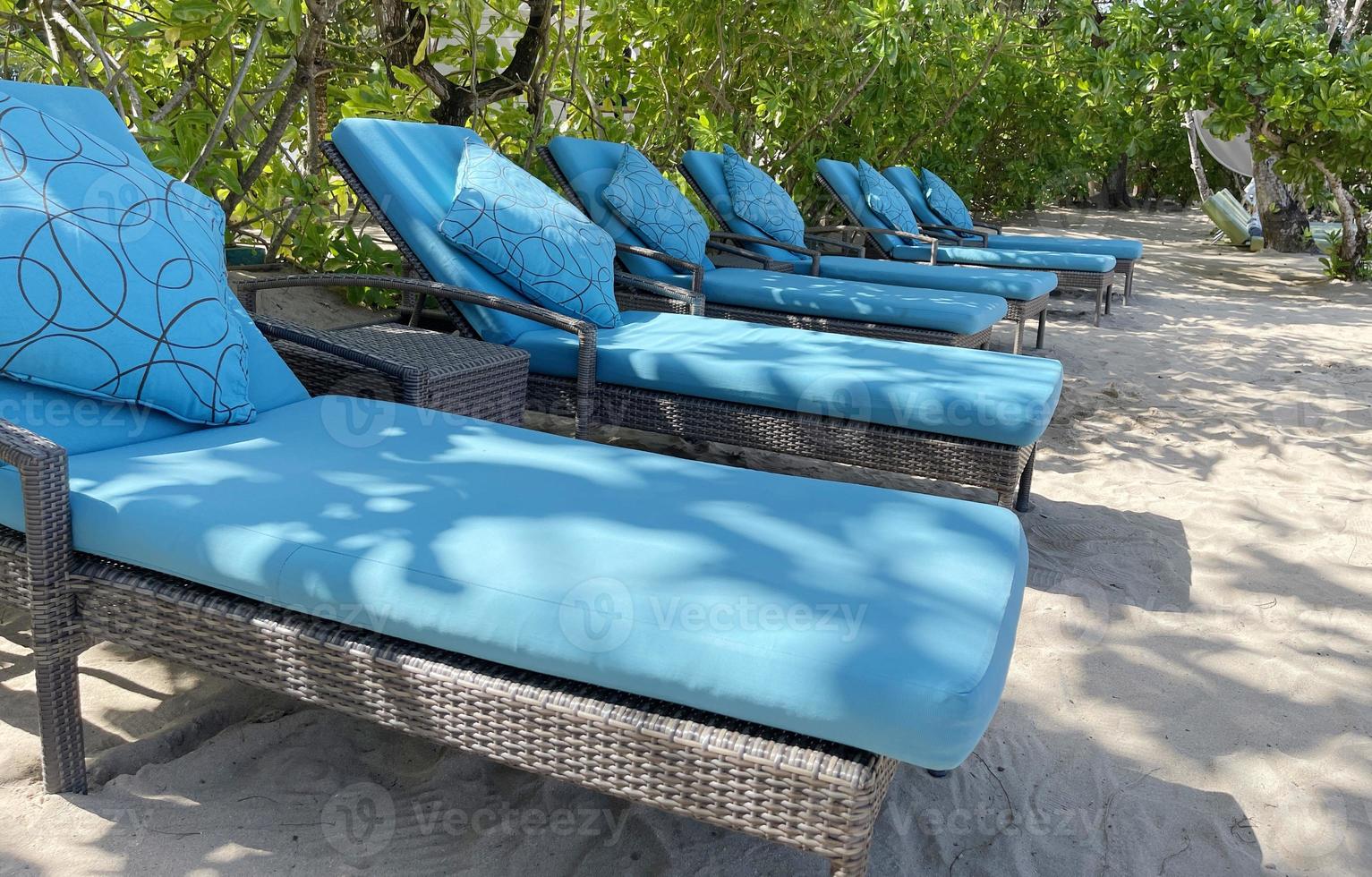 chaises longues ou chaises de plage sur la plage de sable blanc lors d'une chaude journée d'été dans un hôtel tropical de luxe photo