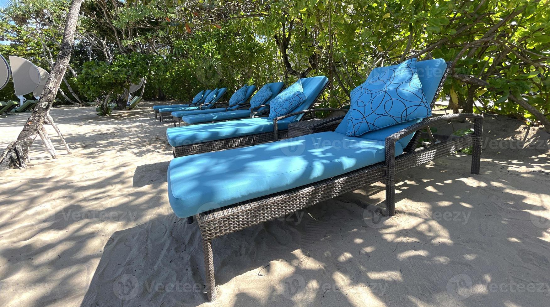 chaises longues ou chaises de plage sur la plage de sable blanc lors d'une chaude journée d'été dans un hôtel tropical de luxe photo