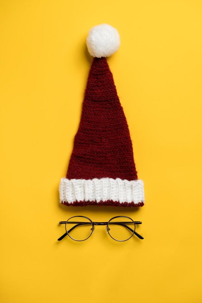 chapeau de père noël et les lunettes rondes en dessous ressemblent à un visage sur fond jaune. vente de nouvel an d'accessoires pour les yeux. photo