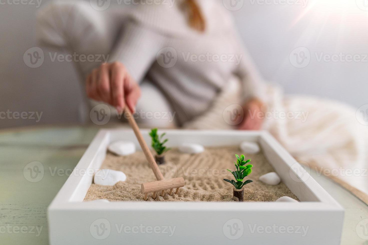 main d'une belle jeune femme utilisant son jardin zen à la maison. belle jeune femme souriante se détendant avec son jardin zen et profitant de sa journée photo