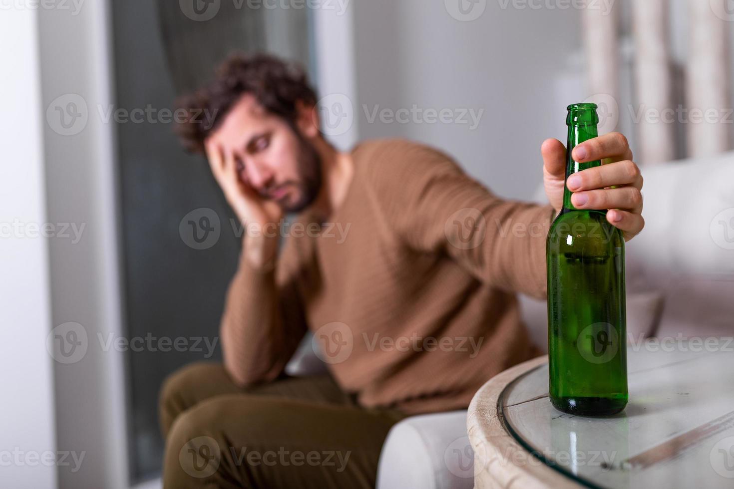 homme alcoolique cherchant une bouteille de bière, homme buvant seul à la maison. alcoolisme, dépendance à l'alcool et concept de personnes - homme alcoolique avec une bouteille de bière buvant seul à la maison photo