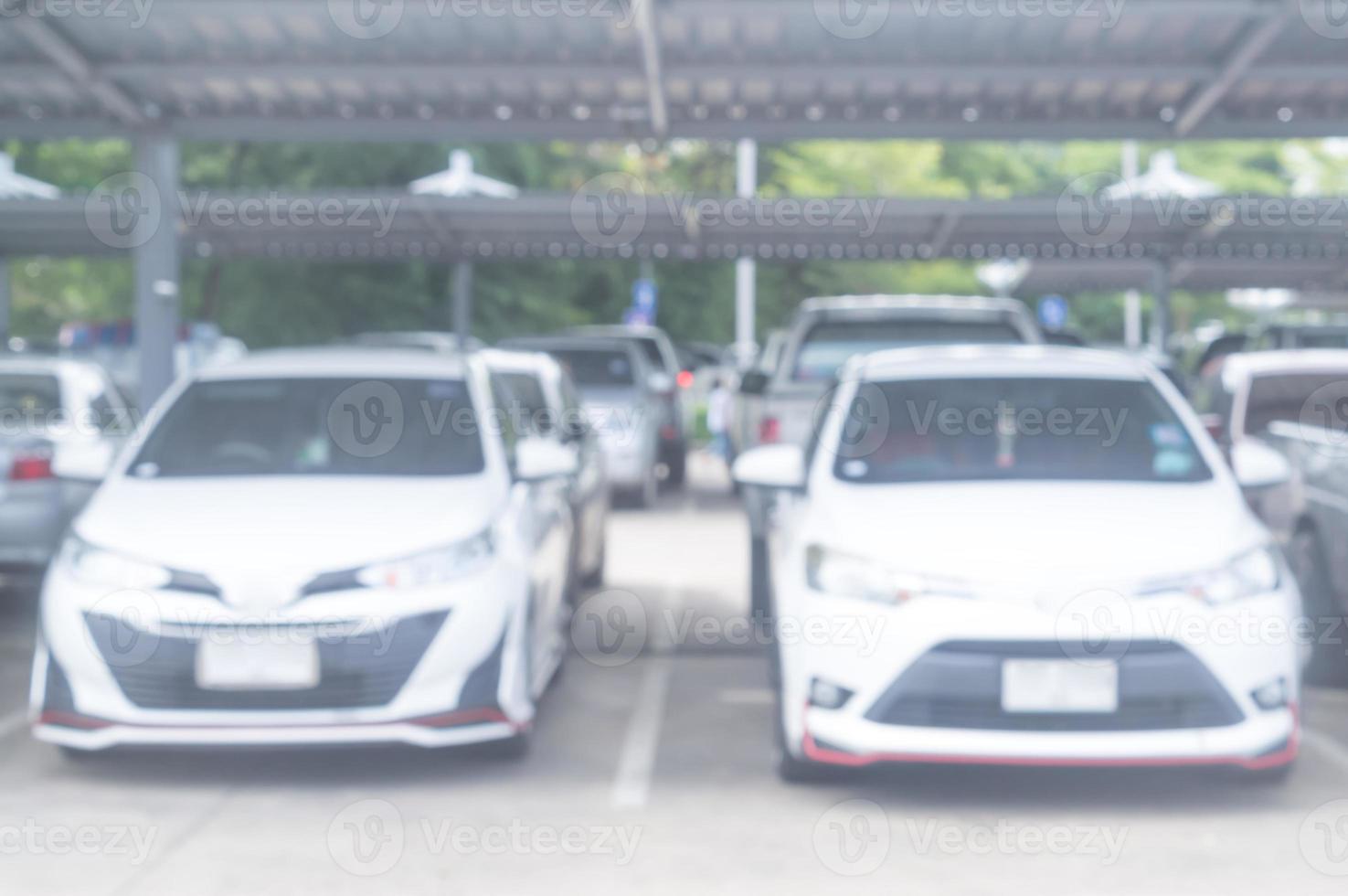 une photo floue de voitures se garant dans un espace ouvert ou un parking extérieur avec toit est prise devant un bureau, une université, une école, un grand magasin ou un hôpital