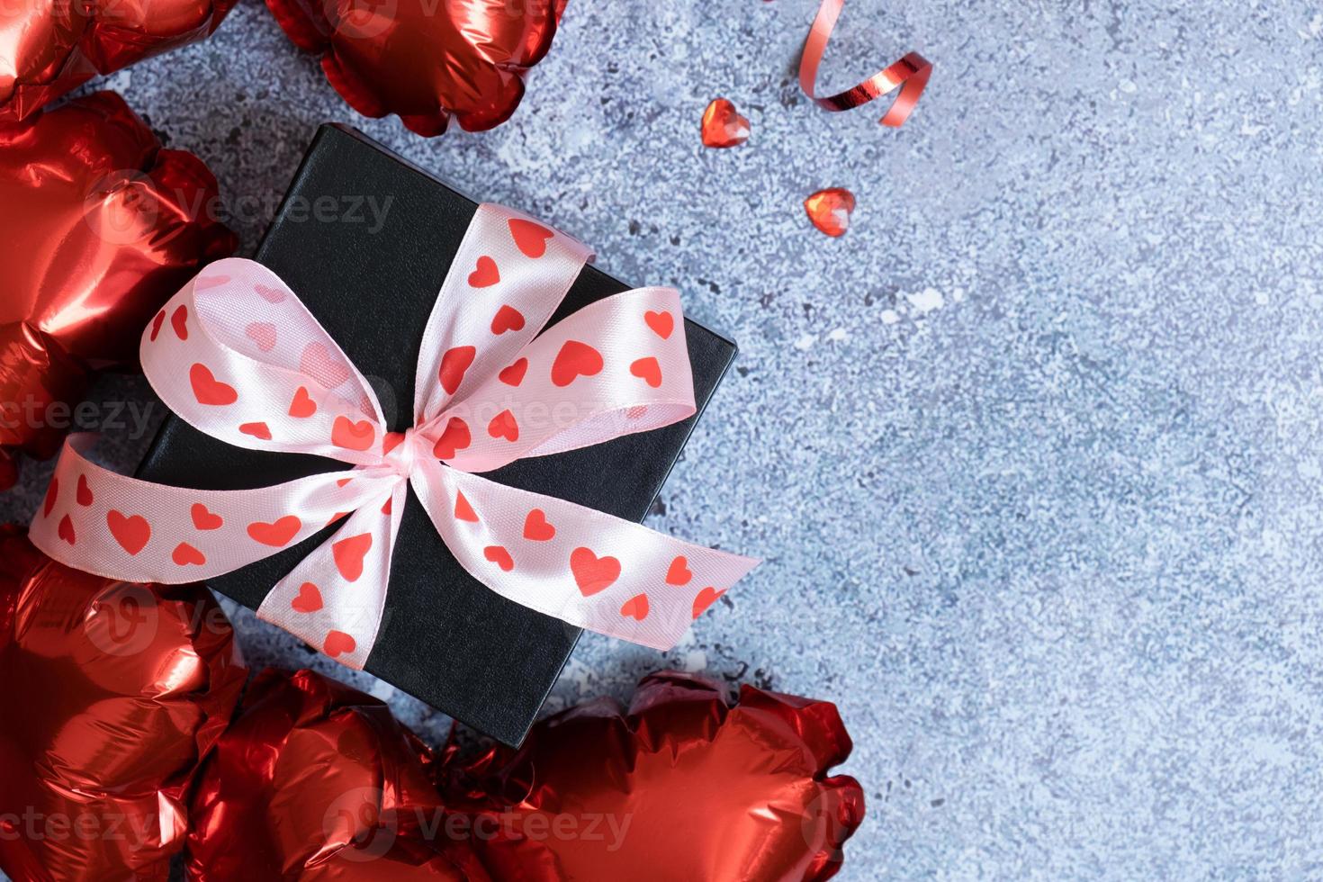 ballons en forme de coeur rouge et boîte-cadeau sur fond de béton. modèle de carte de voeux saint valentin. copie espace photo