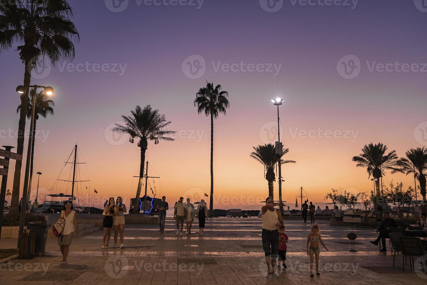 touristes marchant sur le sentier menant aux palmiers qui poussent sur la plage photo