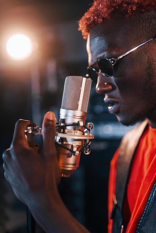 avoir une pratique vocale. jeune artiste afro-américain répétant dans un studio d'enregistrement photo