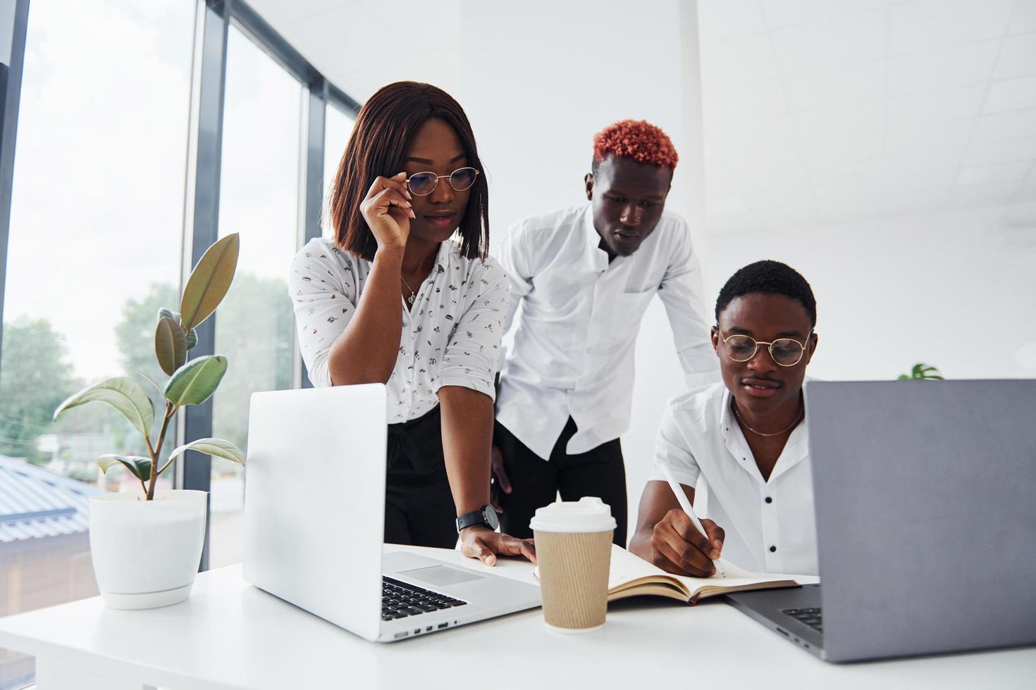 en utilisant le même ordinateur portable pour le projet. groupe de gens d'affaires afro-américains travaillant ensemble au bureau photo