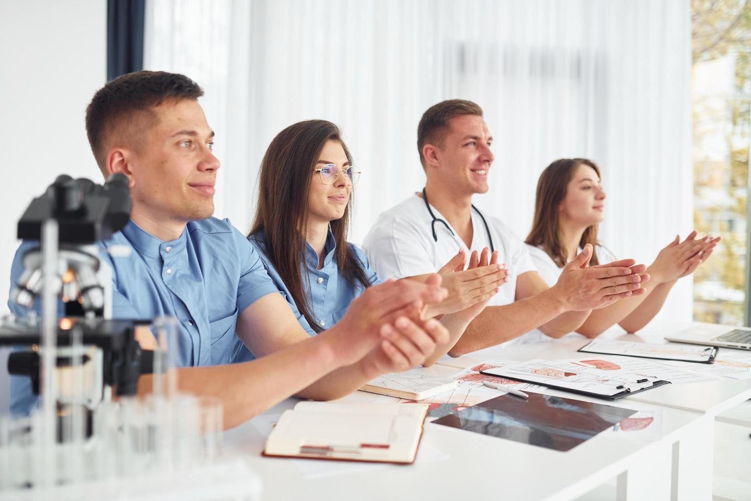 assis près de la table. groupe de jeunes médecins travaille ensemble dans le bureau moderne photo