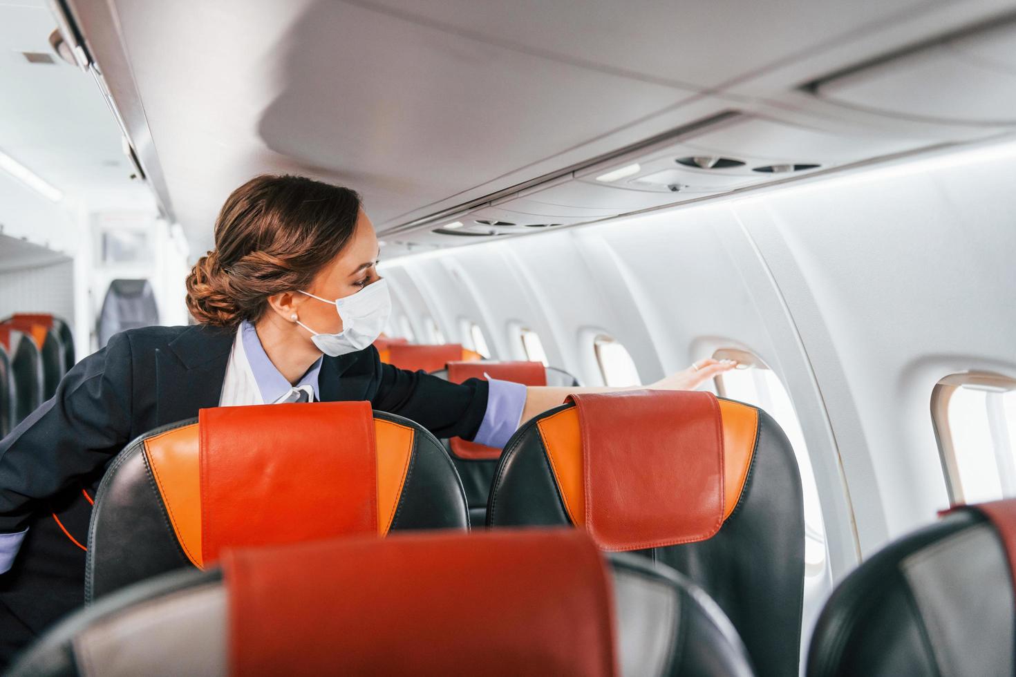 en masque. jeune hôtesse de l'air sur le travail dans l'avion passager photo