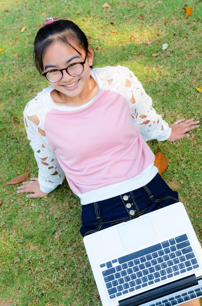 jolie fille est heureuse avec un ordinateur portable sur l'herbe photo
