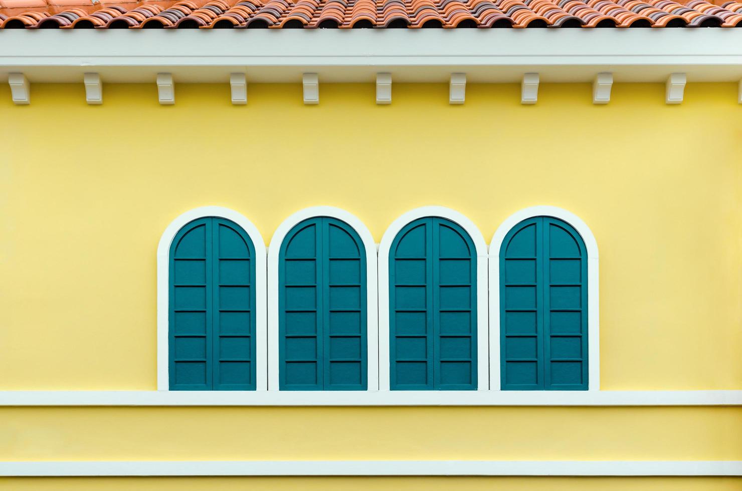 quatre fenêtres cintrées vertes sur un mur jaune photo