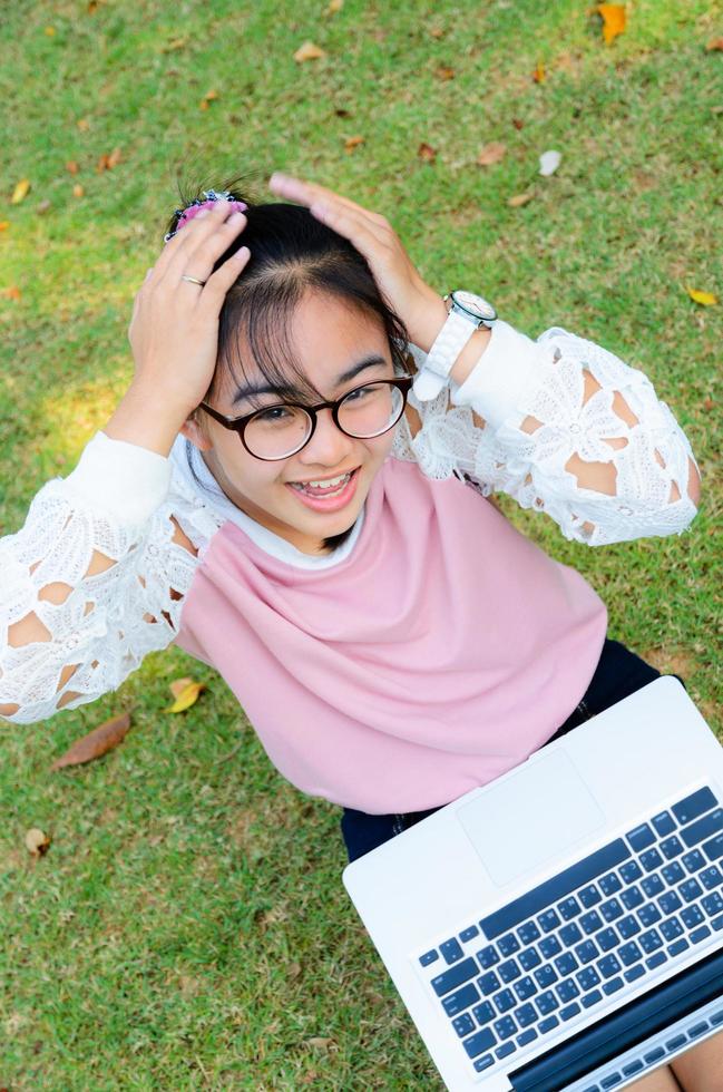 jolie fille est heureuse avec un ordinateur portable sur l'herbe photo