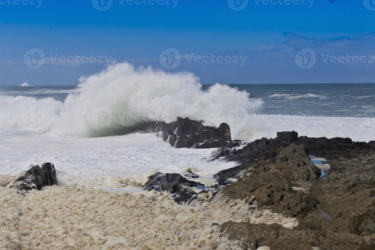 une grosse vague frappe des rochers sur la côte photo