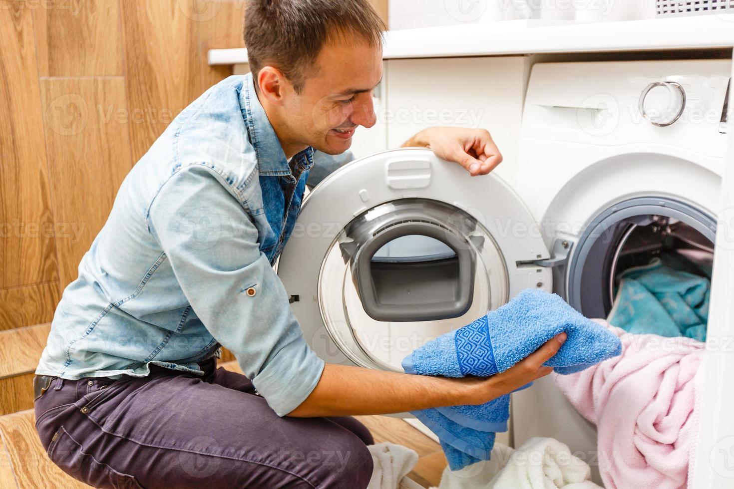 homme chargeant des chiffons dans la machine à laver. vue de l'intérieur de la machine à laver. photo
