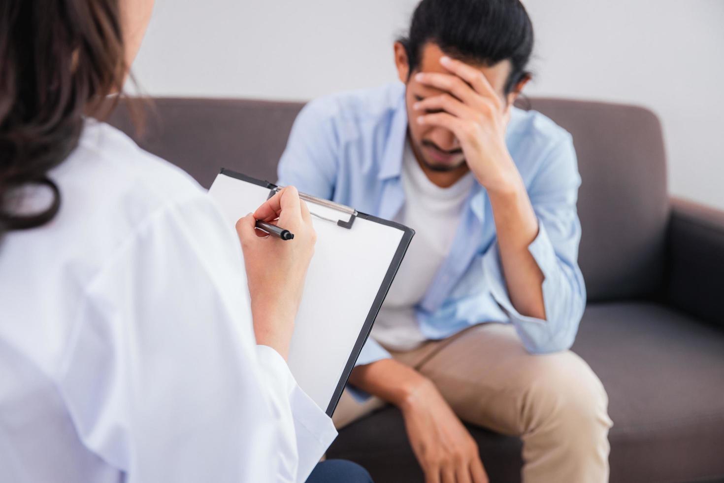 note de femme psychologue professionnel menant une consultation et parler avec un patient homme asiatique photo
