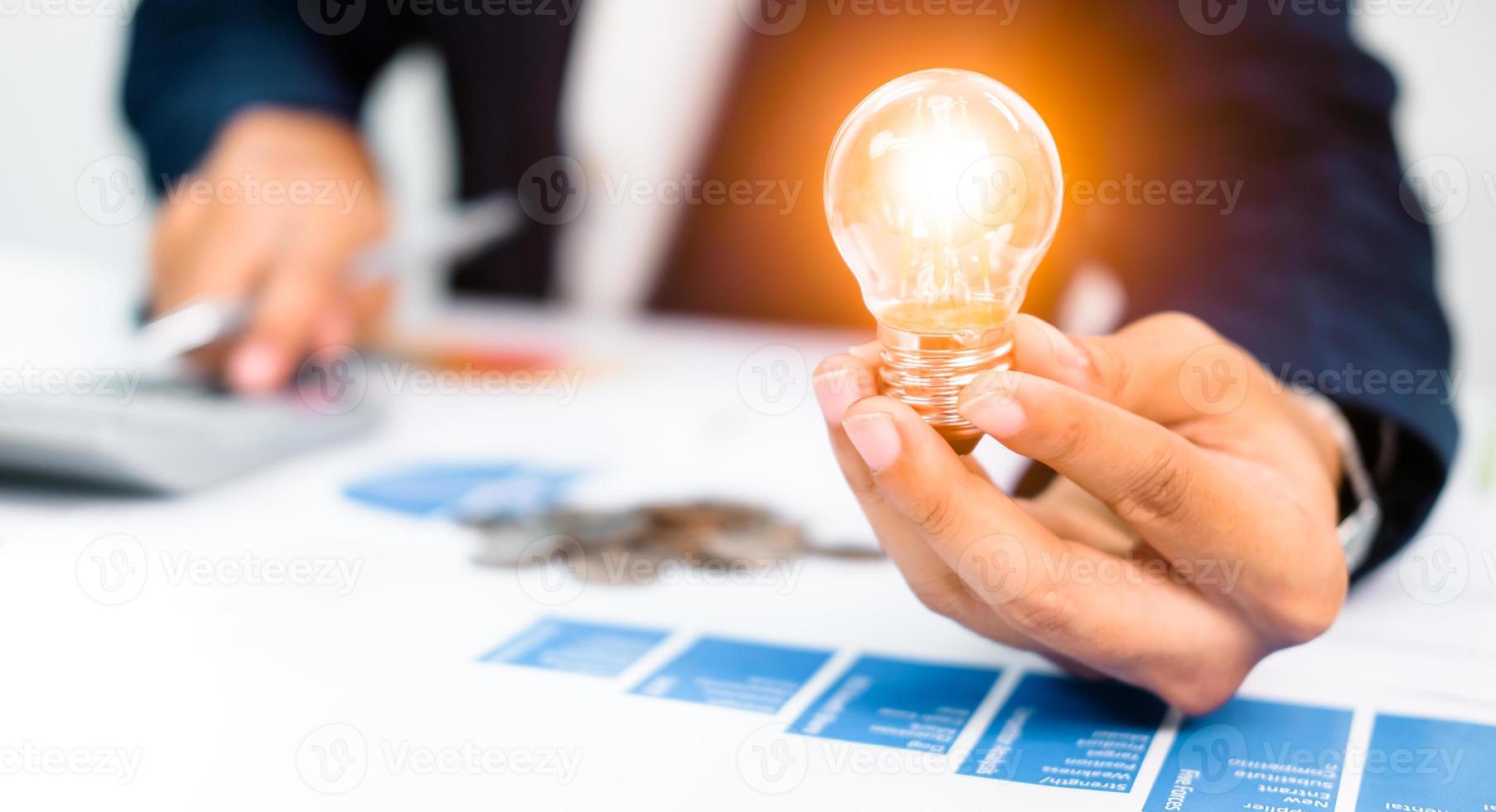 homme d'affaires utilisant un stylo à partir de statistiques financières, tenant une ampoule, avec des idées, avec innovation et créativité. photo