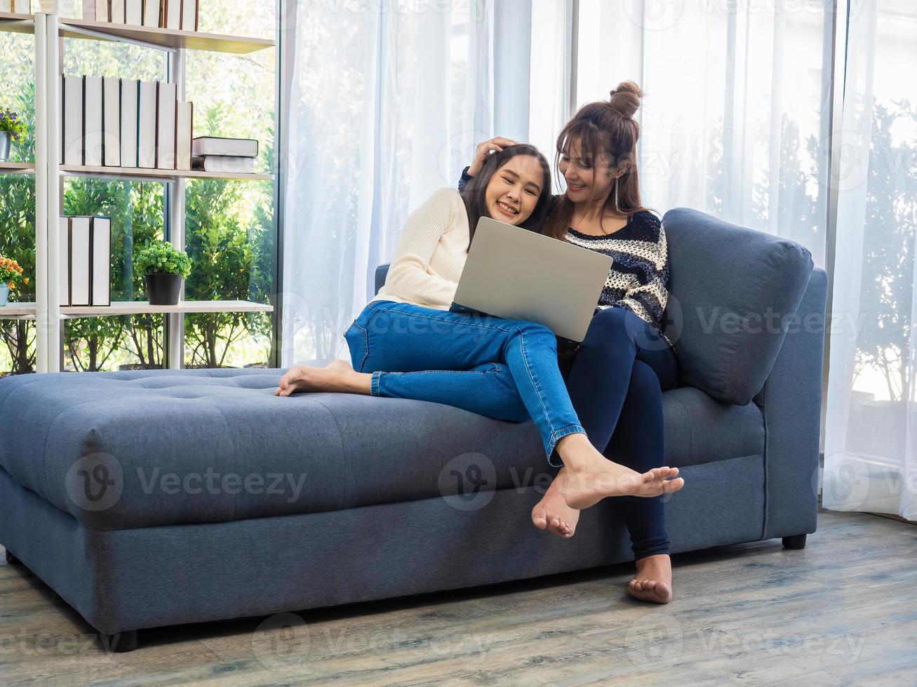 belles jeunes femmes asiatiques couple de lesbiennes lgbt couple heureux assis sur le canapé dans le salon, en utilisant l'ordinateur portable acheté en ligne à la maison. couple de lesbiennes lgbt ensemble à l'intérieur concept photo