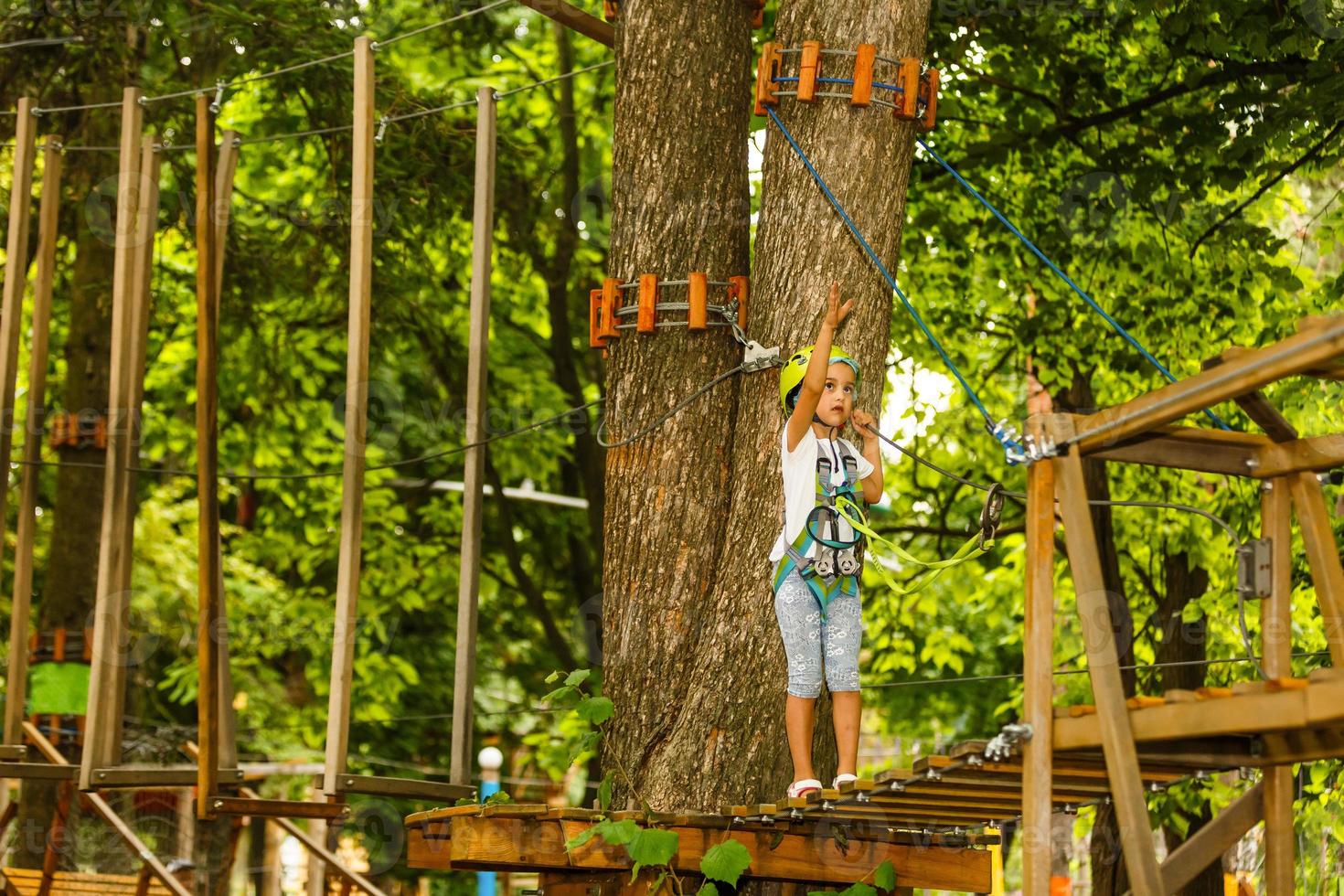 adorable petite fille profitant de son temps dans le parc d'aventure d'escalade le jour d'été chaud et ensoleillé photo