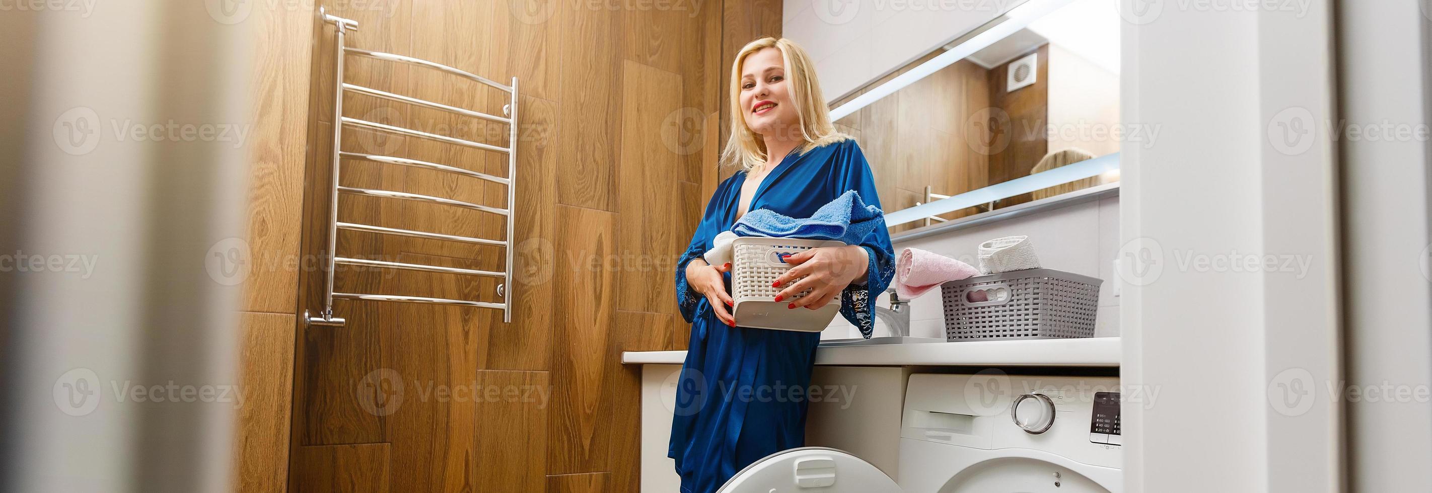 belle jeune femme sourit en faisant la lessive à la maison. photo