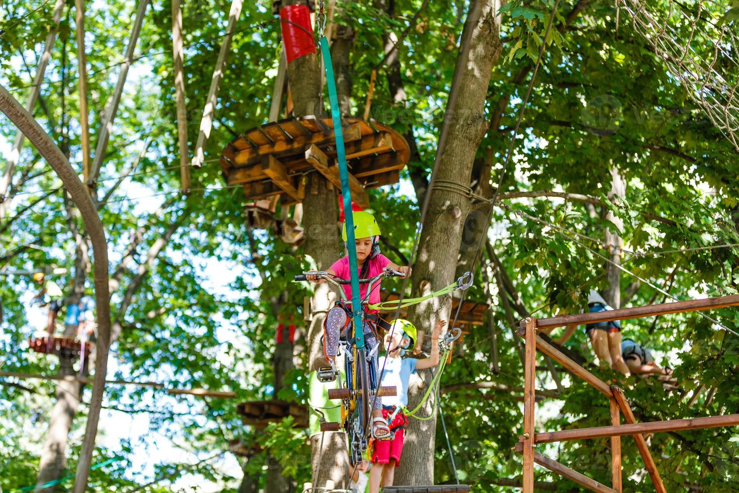 petits enfants heureux dans un parc à cordes sur fond de bois photo