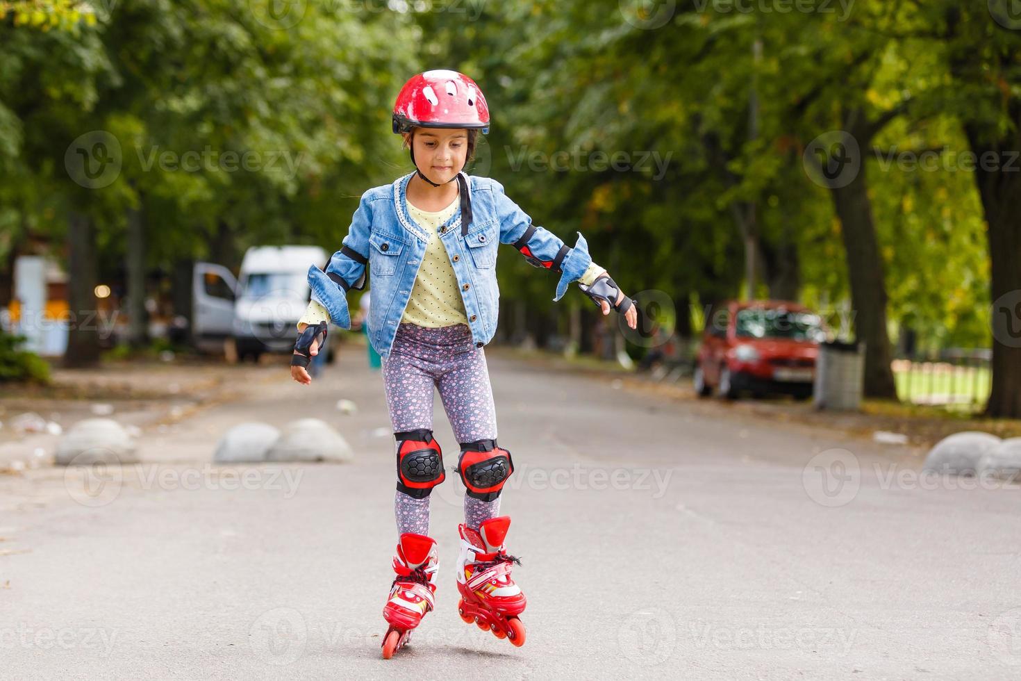 drôle de petite jolie fille sur patins à roulettes en casque à cheval dans un parc. concept de mode de vie sain. photo