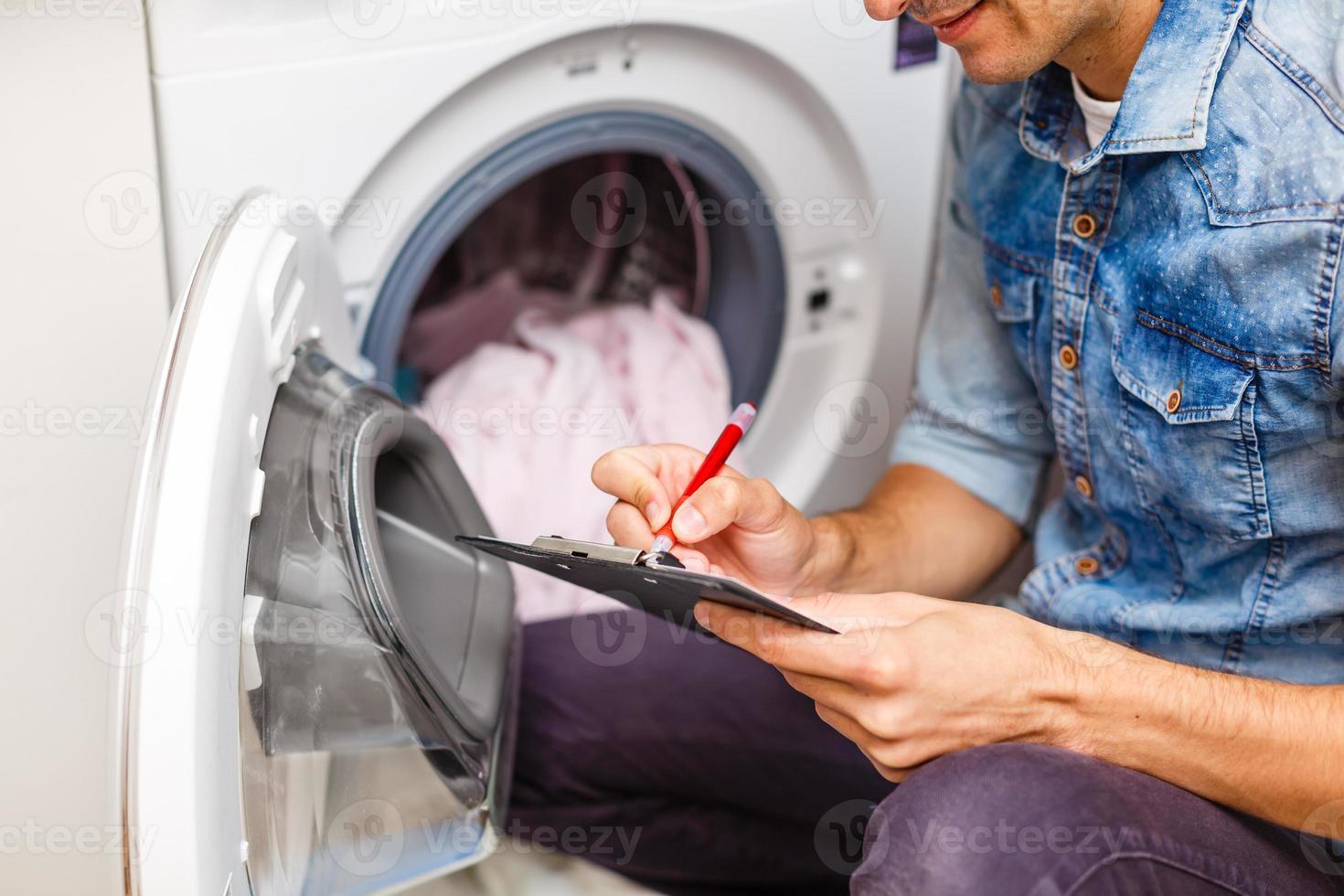 jeune entrepreneur réparant une machine à laver dans la cuisine photo