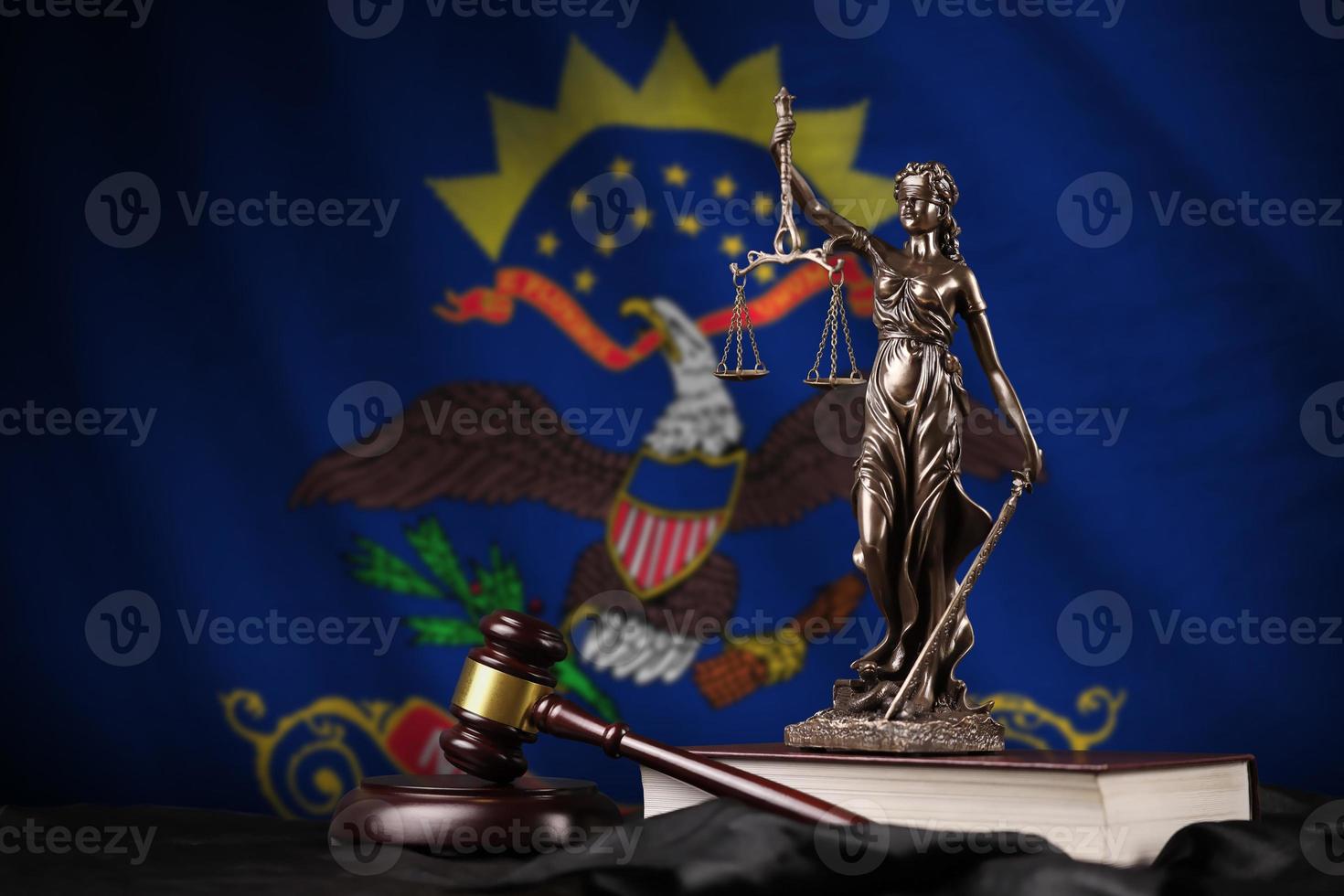 drapeau d'état américain du dakota du nord avec statue de dame justice, constitution et marteau de juge sur draperie noire. concept de jugement et de culpabilité photo