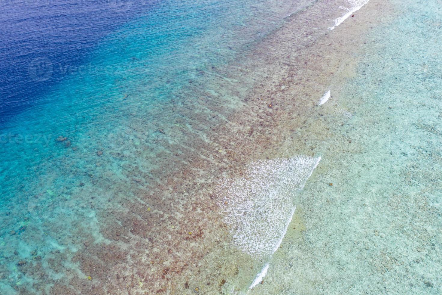 vue aérienne sur la mer, vue de dessus sur fond d'océan nature incroyable. couleurs de l'eau bleu vif, plage du lagon avec des vagues éclaboussant à la journée ensoleillée. photo de drone volant, paysage naturel incroyable avec récif de corail