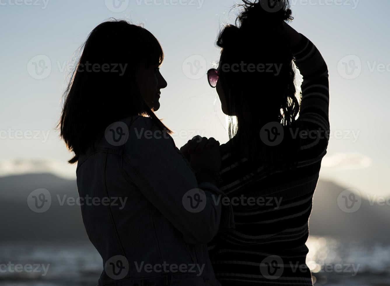 silhouettes de copines au coucher du soleil étreignant. photo