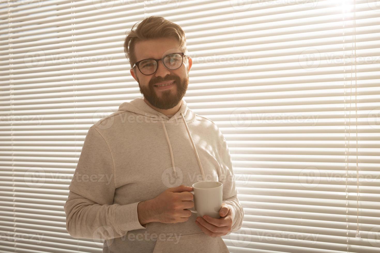 jeune homme élégant avec des stands de barbe et souriant. concept de profiter du soleil du matin et de la positivité photo