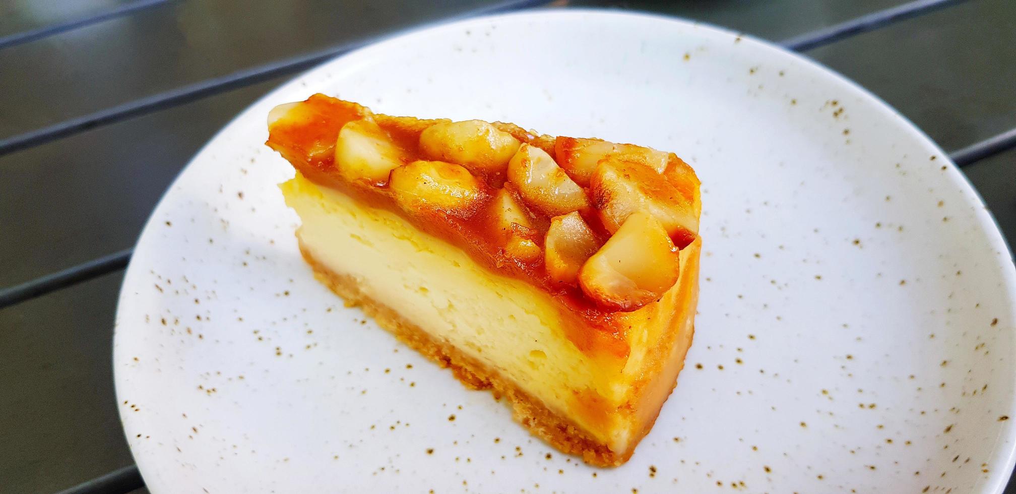 tranche de gâteau au fromage macadamia sur un plat blanc ou une assiette avec espace de copie à droite. dessert sucré et plats faits maison au café. photo