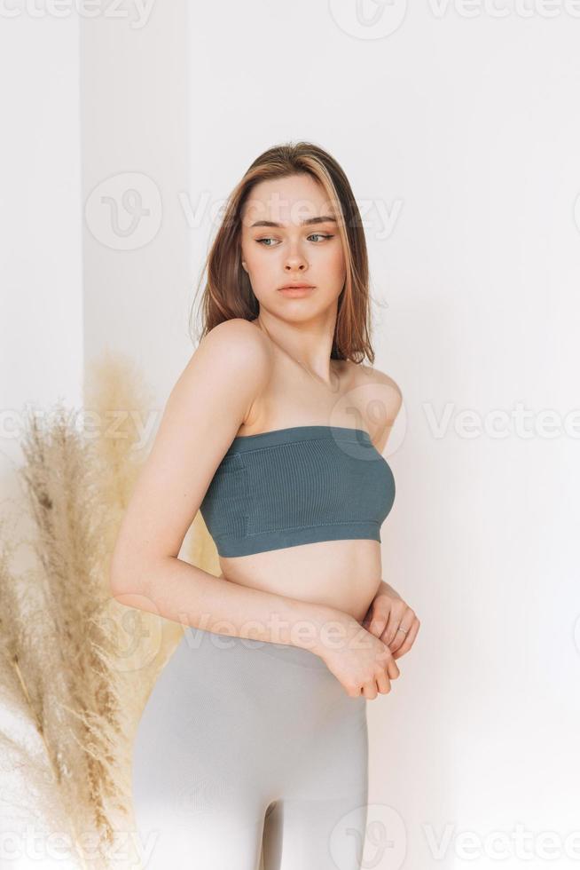 belle jeune femme beauté mannequin aux cheveux longs en vêtements de sport regardant la caméra sur le fond blanc photo