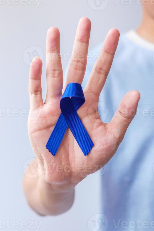 mars mois de sensibilisation au cancer colorectal, femme tenant un ruban bleu foncé pour soutenir les personnes vivant et malades. soins de santé, espoir et concept de la journée mondiale du cancer photo