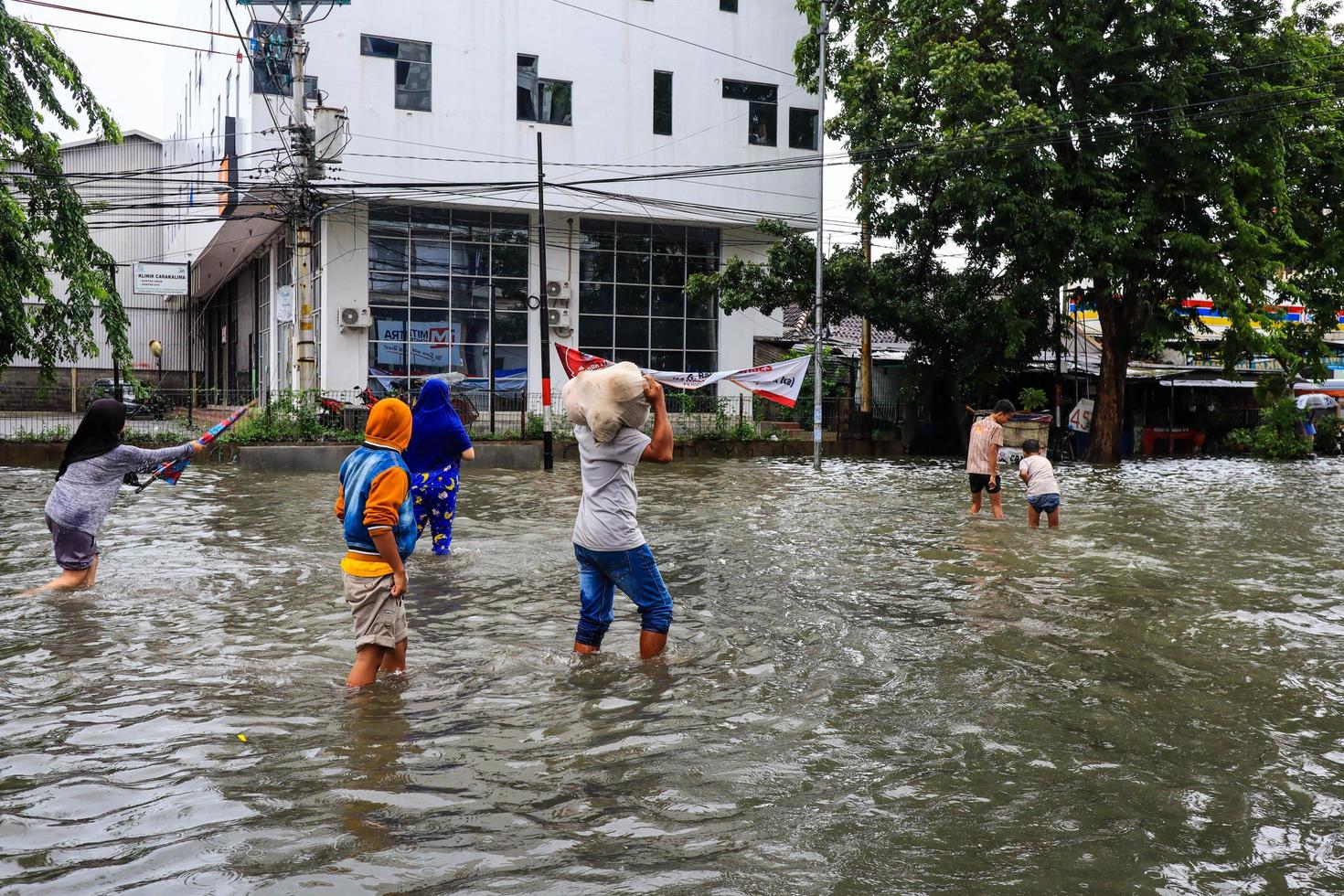 semarang, décembre 2022. plusieurs personnes transportent des sacs remplis de nourriture et de vêtements pour se préparer à l'évacuation après l'inondation de leur maison photo