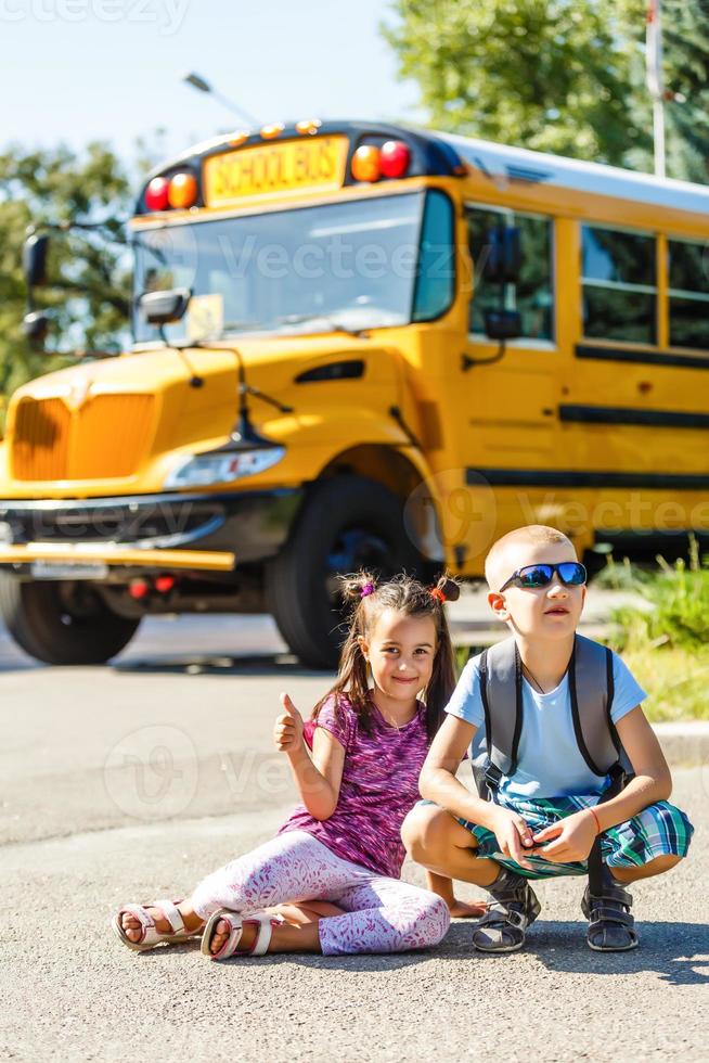 belle petite écolière avec ses camarades de classe près du bus scolaire photo