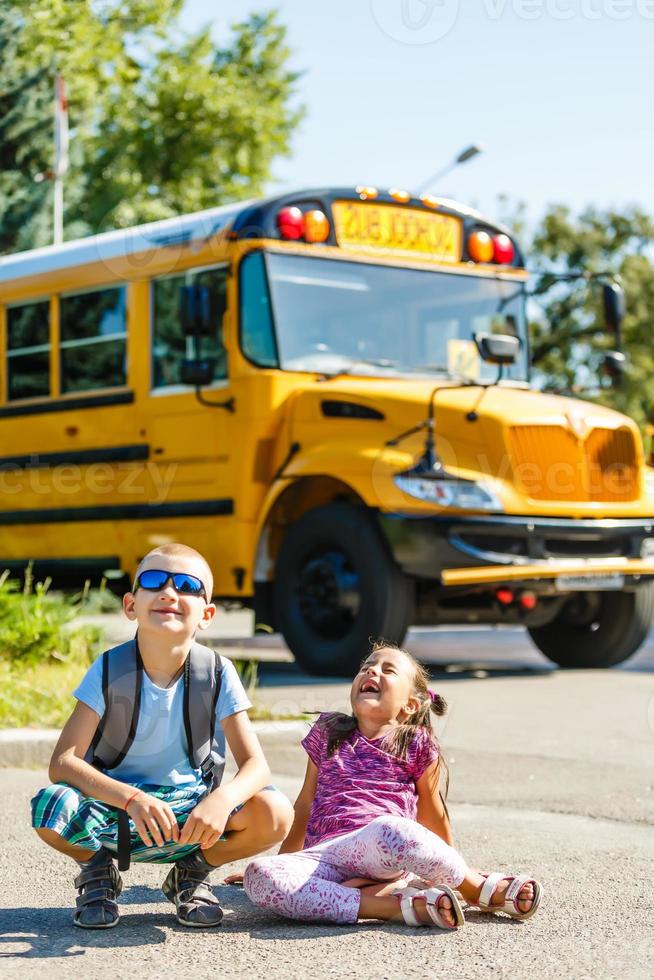 belle petite écolière avec ses camarades de classe près du bus scolaire photo