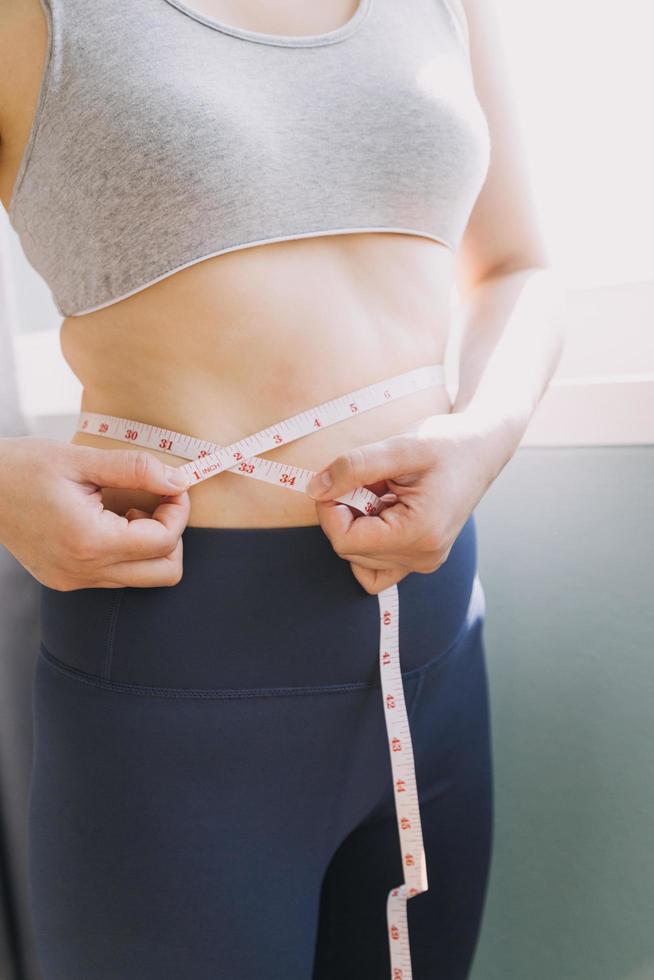 belle grosse femme avec ruban à mesurer, elle utilise sa main pour presser l'excès de graisse isolé sur fond blanc. elle veut perdre du poids, le concept de chirurgie et décomposer les graisses sous le photo