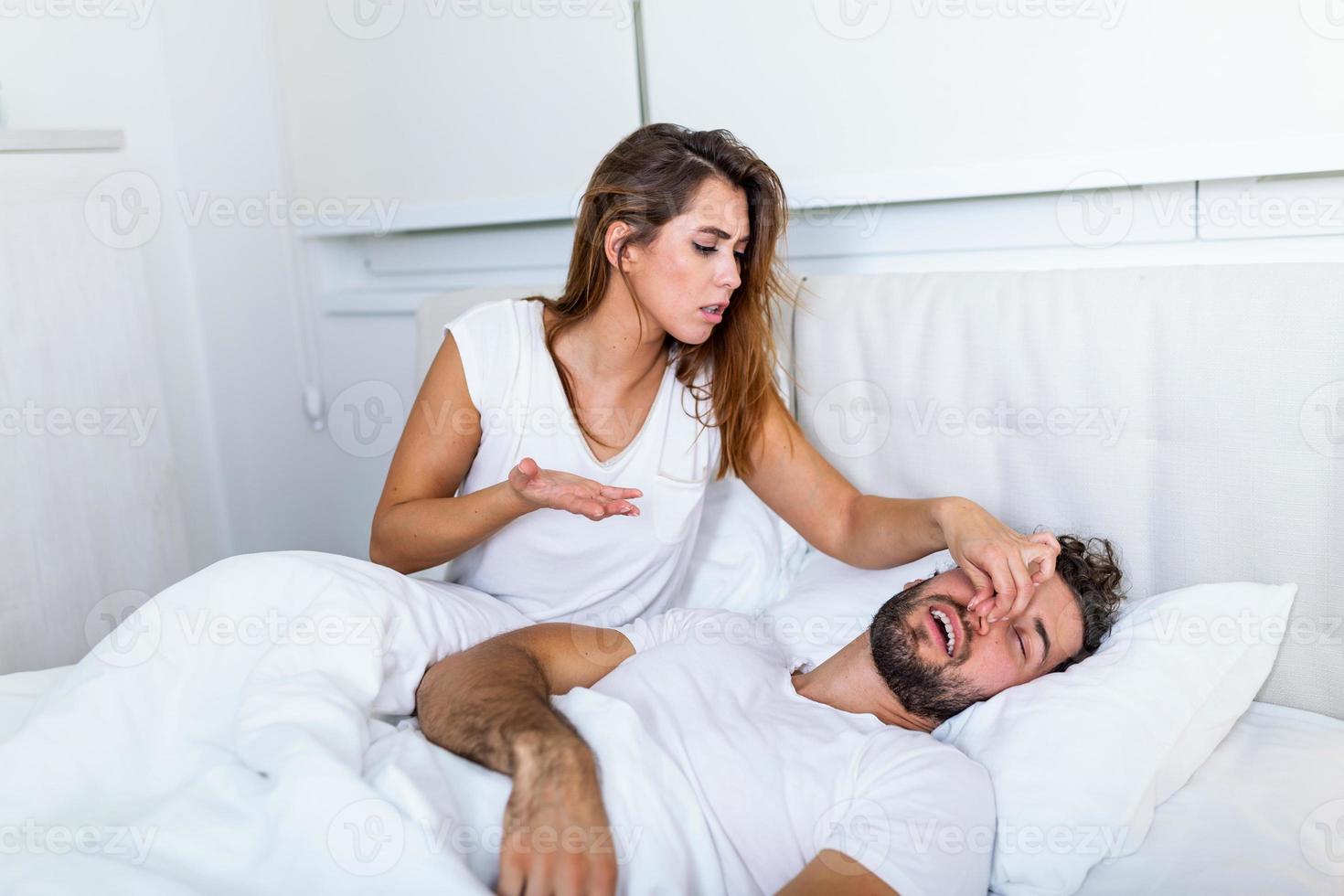 couple au lit, l'homme ronfle et la femme ne peut pas dormir. ronflement homme et jeune femme. couple dormant dans son lit. la jeune fille ne peut pas dormir à cause du ronflement de son homme qui se tient le nez. problème d'homme qui ronfle photo