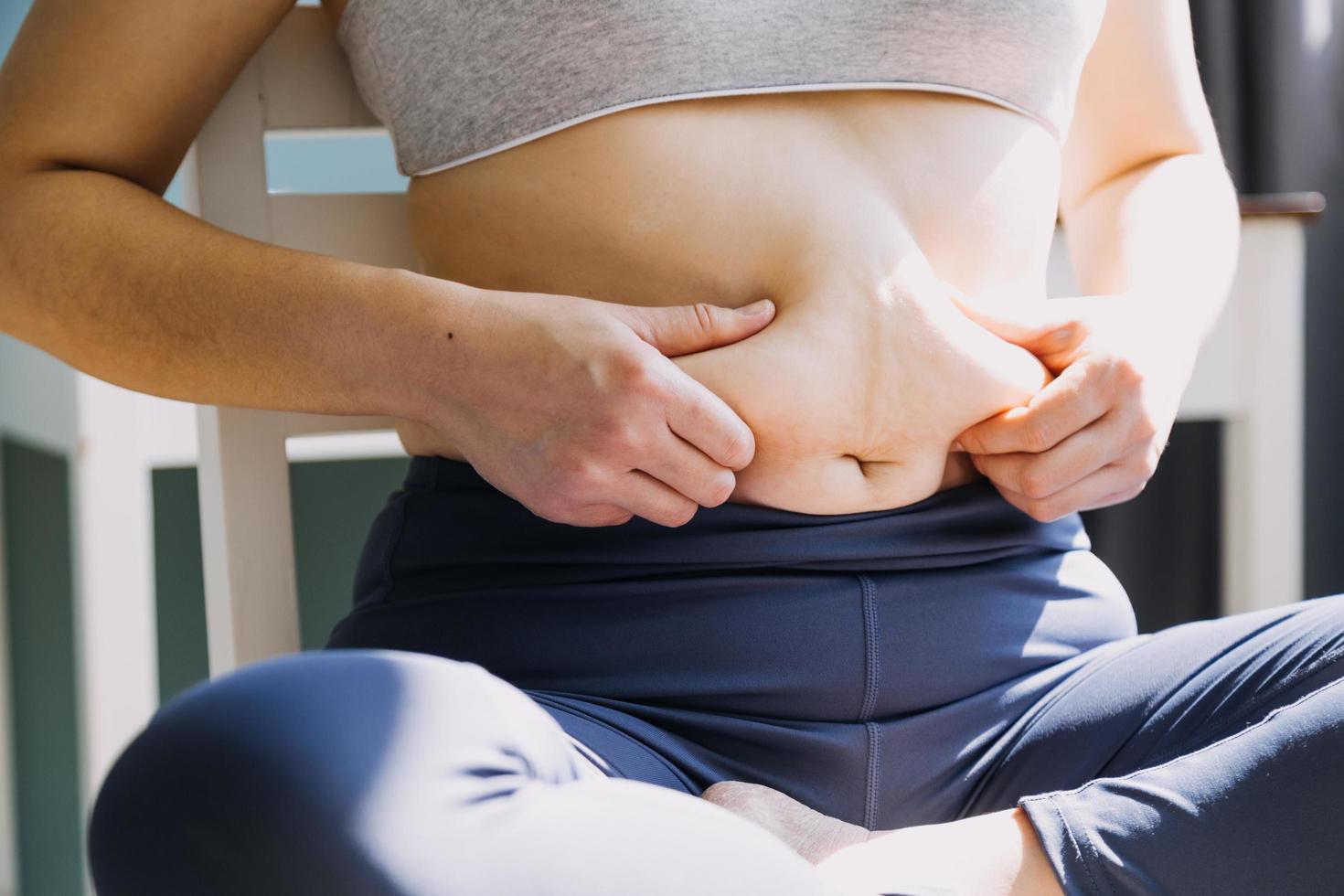 belle grosse femme avec ruban à mesurer, elle utilise sa main pour presser l'excès de graisse isolé sur fond blanc. elle veut perdre du poids, le concept de chirurgie et décomposer les graisses sous le photo