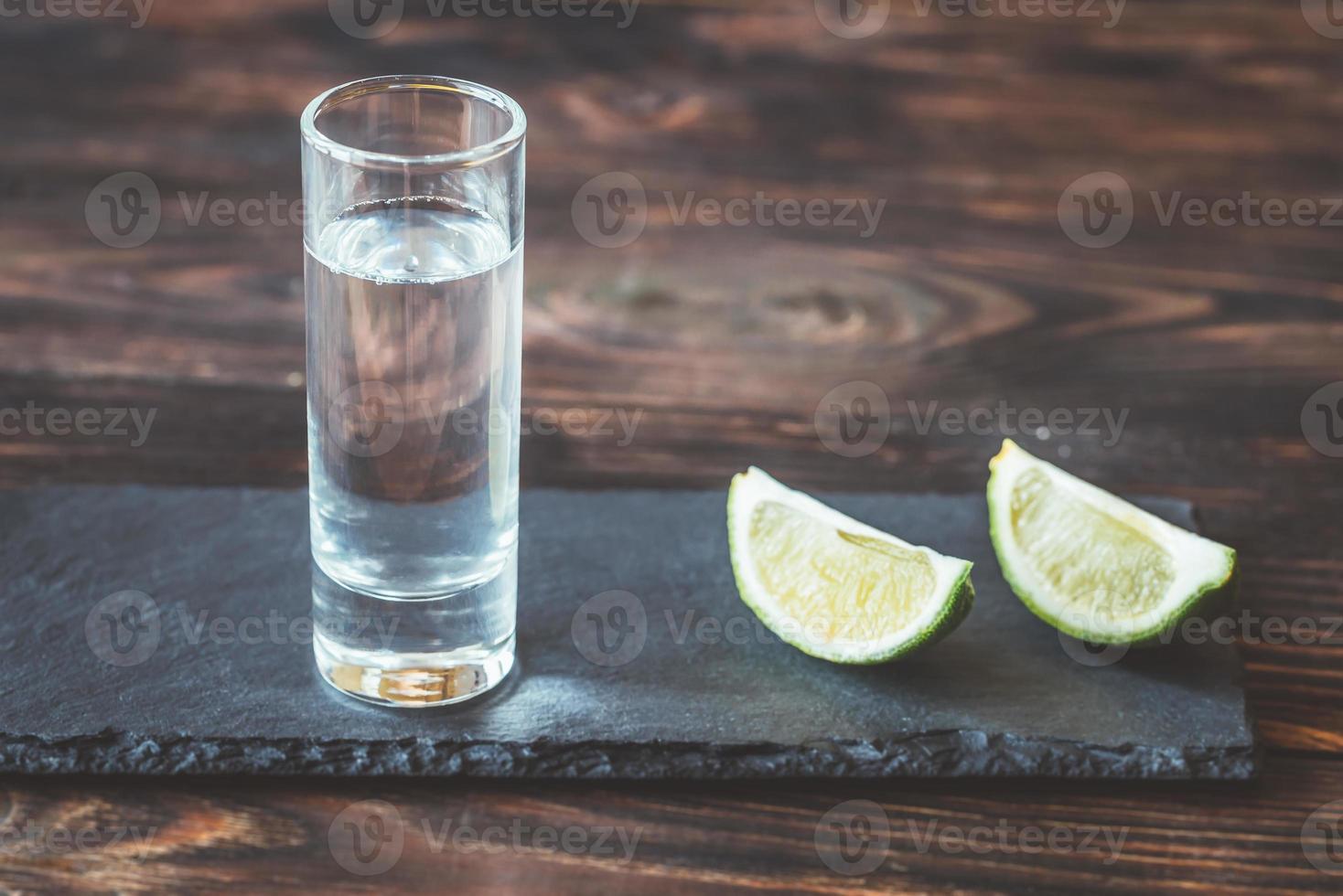 verre de tequila avec des quartiers de citron vert photo