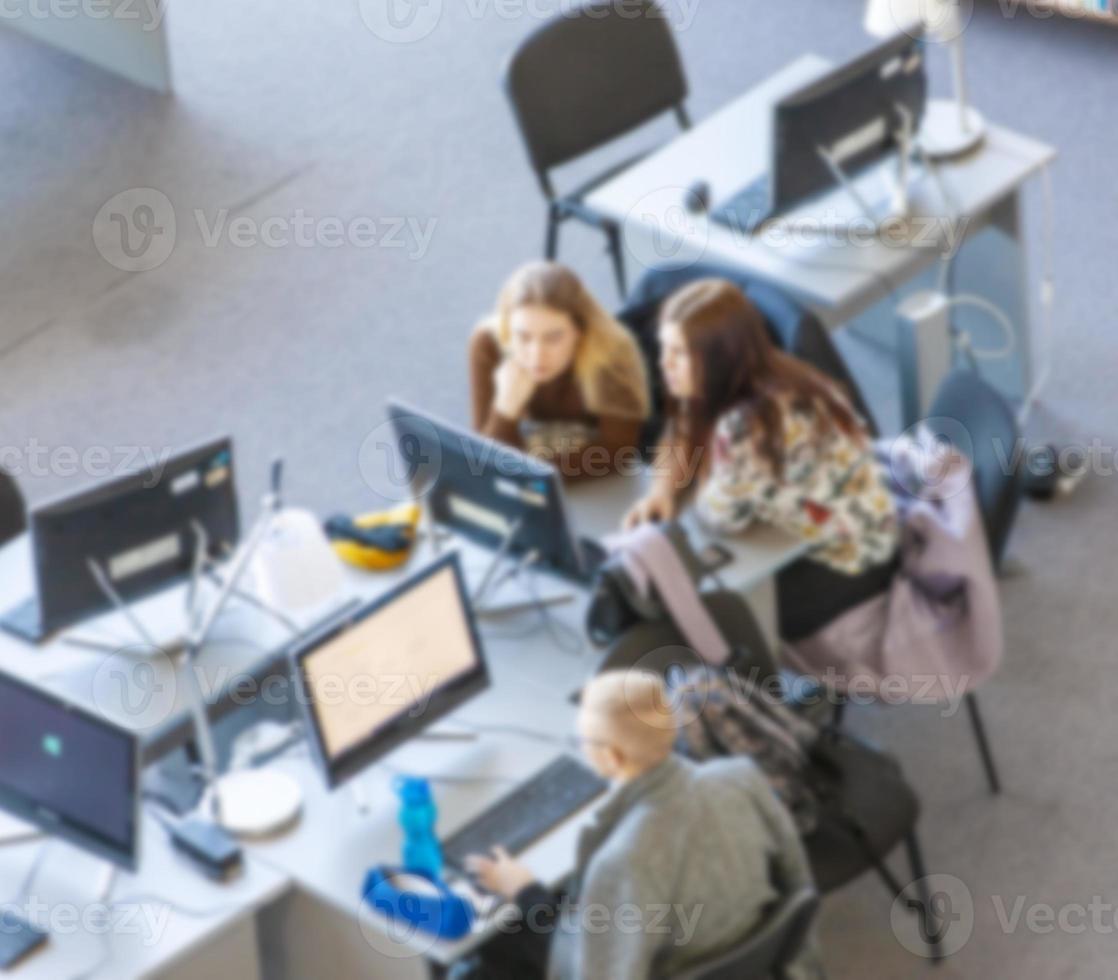 Étudiant estompé pour l'ordinateur dans la bibliothèque photo